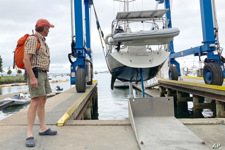 Robin Berthet, of Sheffield, Mass., watches as his sailboat is hauled out of the water onto dry land in advance of an expected…