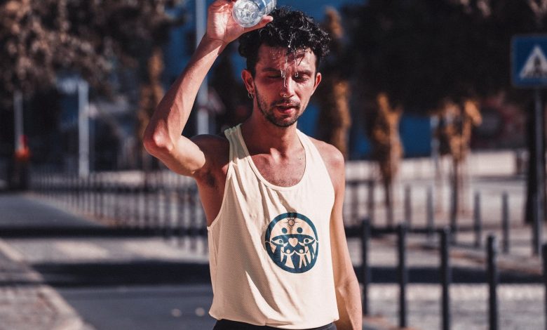 tired sportsman pouring water on head after running training