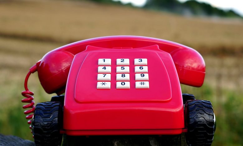 red rotary phone with black wheels near brown grasses during day time