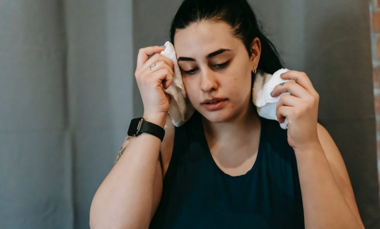 tired plump ethnic woman in gym with towel
