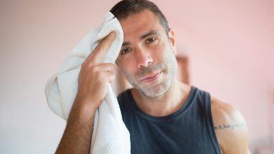 man in blue tank top holding white towel