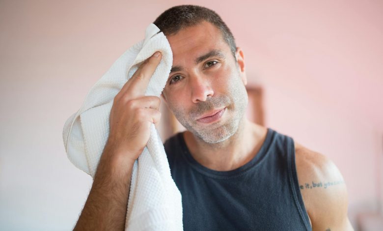 man in blue tank top holding white towel